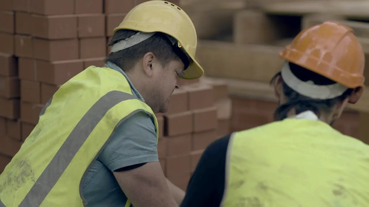 Two site workers in hard hats and hi-vis vests